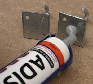 Adhesivo para metal. Aplicación de adhesivo a placas de gancho de metal para demostrar la fuerza del adhesivo.