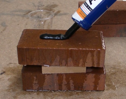 Applying heavy duty construction adhesive on a wet brick.